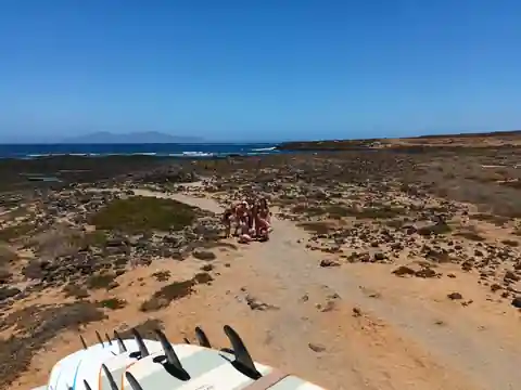 Sesión de surf en grupo en La Laguna, noroeste de Fuerteventura, con alumnas junto a la costa